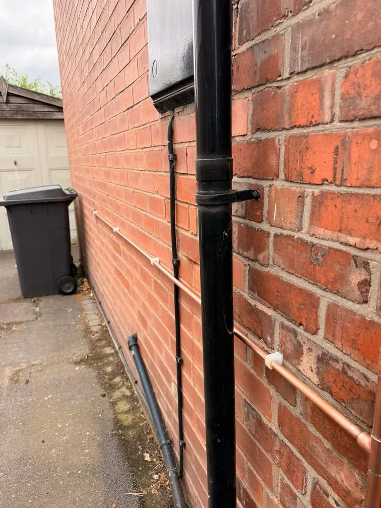 Replacement copper gas main run along exterior brick wall in Holmes Chapel by Warm-Wise