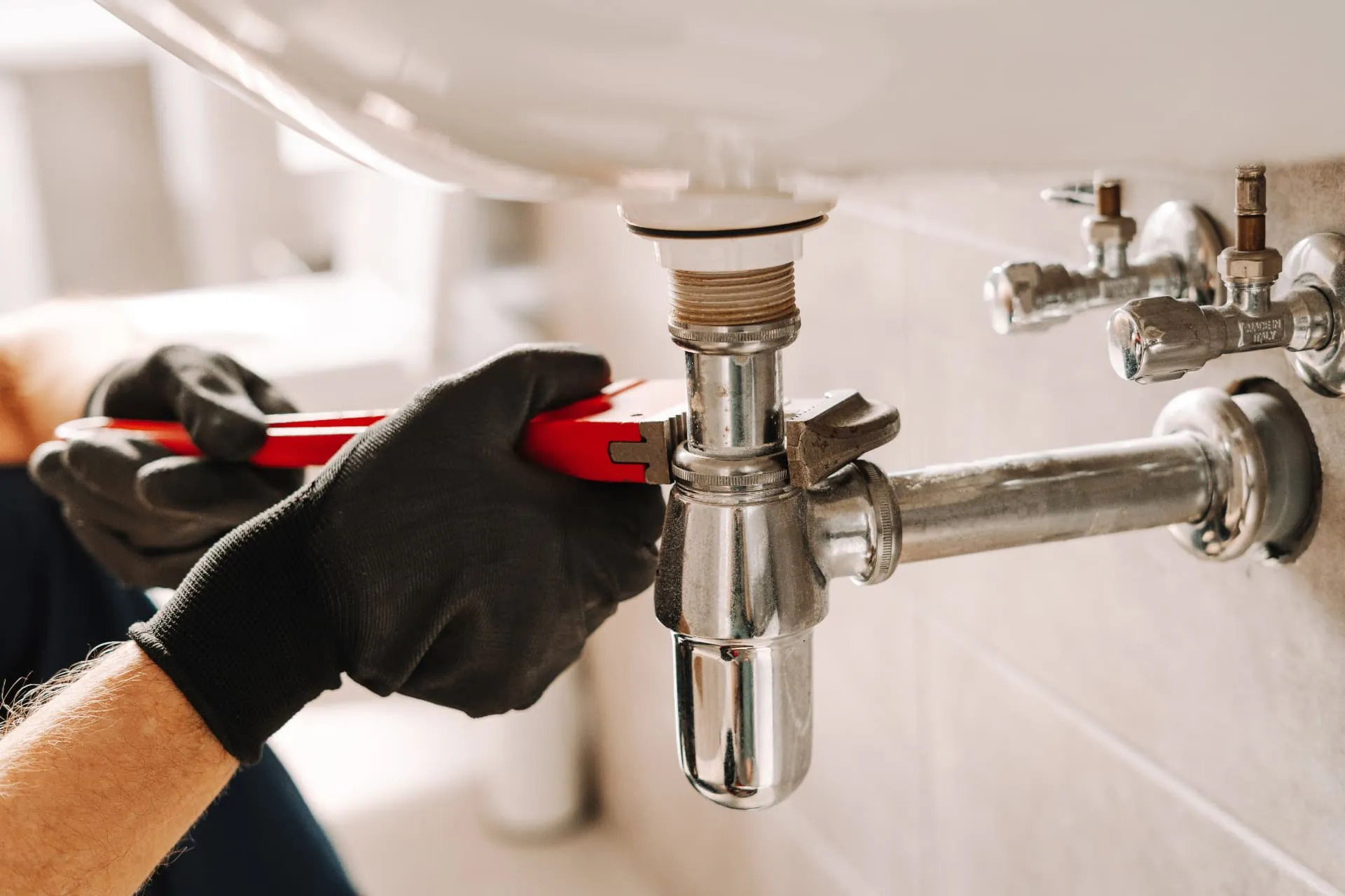 Plumber tightening a basin waste trap