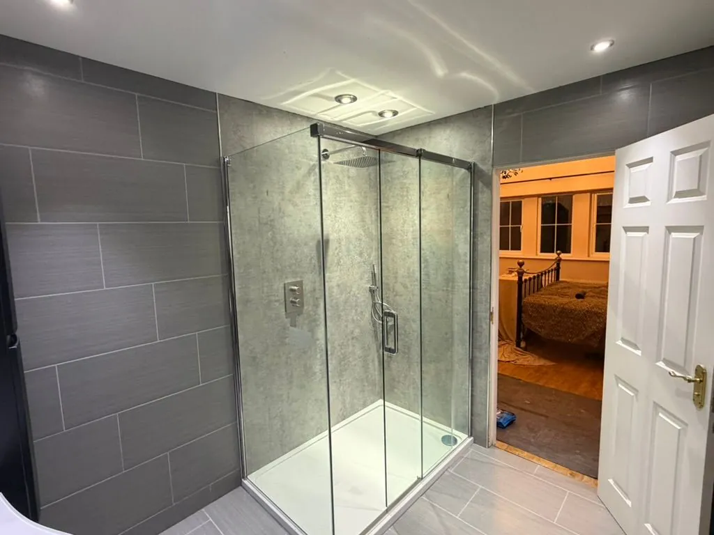 Grey-tiled en-suite with walk-in glass shower enclosure fitted by Warm-Wise