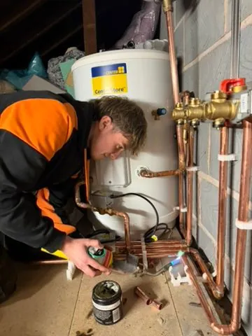 Engineer repairing boiler and hot-water cylinder pipework